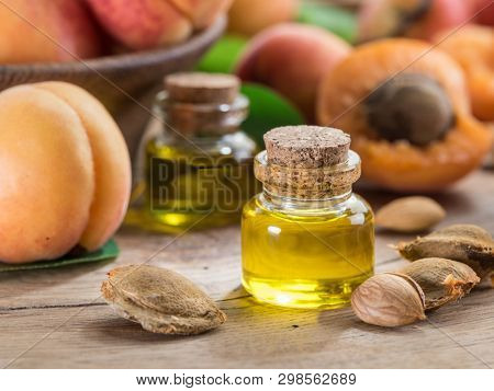 Apricot kernel oil and apricot kernels on wooden background.