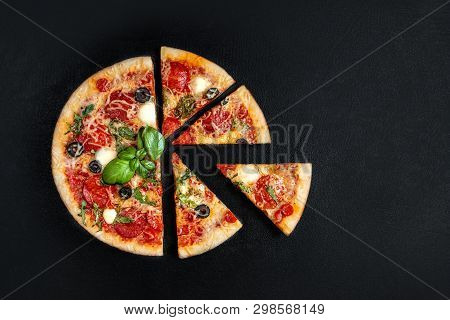 Flatbread Pizza  With  Slices On Black Background. Pepperoni Pizza. Copy Space. Top View