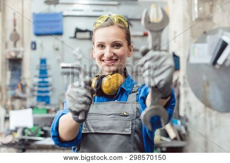Woman mechanic showing tools to the camera holding wrench in her hand