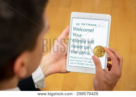 Etrade Website On A Tablet And Businessman Trader Holding Bitcoin.
