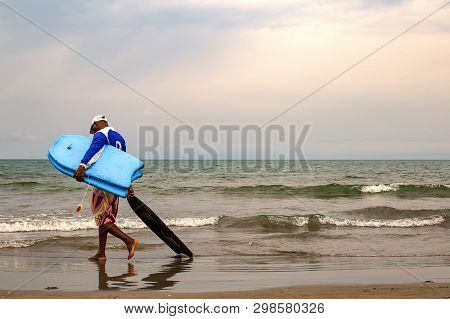 La Boquilla, Cartagena, Colombia- September 18, 2017: A Local Man Walks To Work Carring Some Mini Si