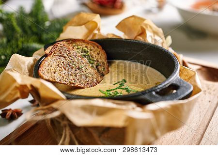 Mushroom Cream Soup with Herbs and Spices in Metal Bowler on Rustic Wooden Background. Homemade Creamy Soup Made of Champignons, Boletus or Ceps with Rye Bread Toasts, Greens and Butter