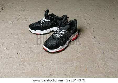Black Sneakers On Thick White With Red Accents Soles On A Gray Concrete Background