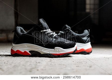 Black Sneakers On Thick White With Red Accents Soles On A Gray Concrete Background