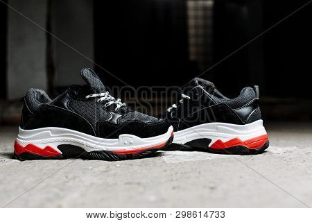 Black Sneakers On Thick White With Red Accents Soles On A Gray Concrete Background