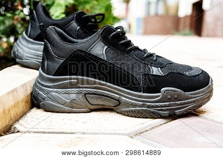 Black Sneakers On Thick Black Soles Against The Background Of Paving Slabs