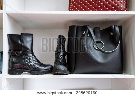 Pair Of Black Leather Shoes With Low Heels And A Black Bag On A White Shelf In The Store