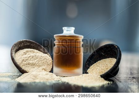 Close Up Of Organic Oil Of Poppy Seeds Or Khus Khus In A Small Glass Bottle With Raw Poppy Seeds And
