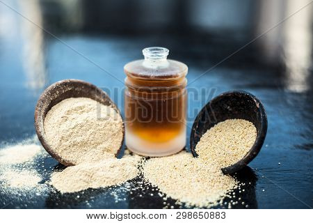 Close Up Of Organic Oil Of Poppy Seeds Or Khus Khus In A Small Glass Bottle With Raw Poppy Seeds And