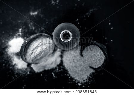 Close Up Of Organic Oil Of Poppy Seeds Or Khus Khus In A Small Glass Bottle With Raw Poppy Seeds And