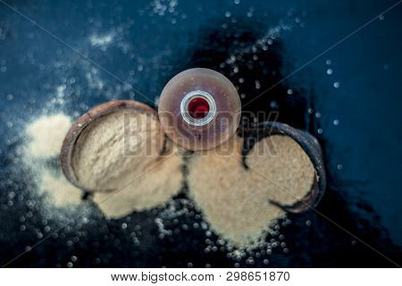 Close Up Of Organic Oil Of Poppy Seeds Or Khus Khus In A Small Glass Bottle With Raw Poppy Seeds And