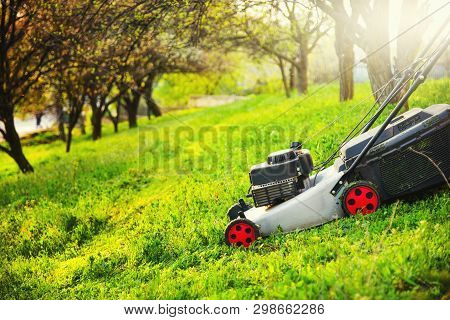 Gardening Care, Mowing Trim Green Grass On Lawn Hill With Lawnmower.