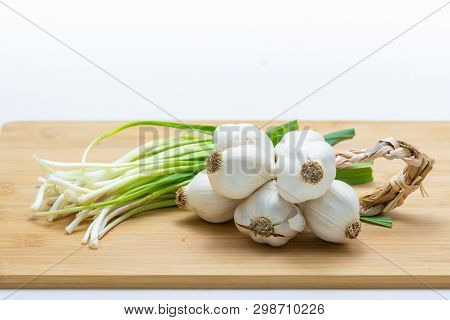 Head Of Garlic And Green Garlic On Cutting Board Preparated For Cooking. Close-up Photo With Selecti