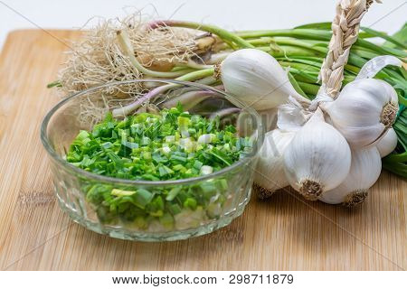 Raw Green Garlic On Cutting Board Preparated For Cooking. Close-up Photo With Selective Focus.