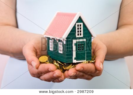 女性の手でお金の山の家