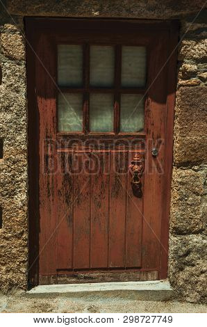 Facade Of Gothic House With Stone Wall And Brown Wooden Door With Peeling Paint, In A Sunny Day At S