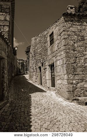Gothic House Made Of Stone With Wooden Door And Deserted Alley, In A Sunny Day At Sortelha. One Of T