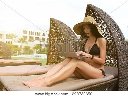 Work And Travel. Incredibly Sexy Girl In A Black Bikini Sits With A Laptop Near The Pool. Find A Tou