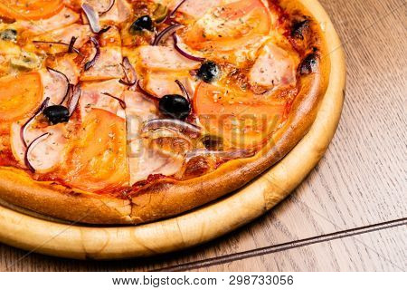 pizza with ham and tomatoes on the wooden background