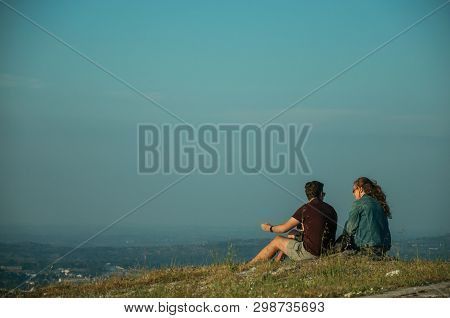 Couple Of People Sitting On Green Lawn At Sunset