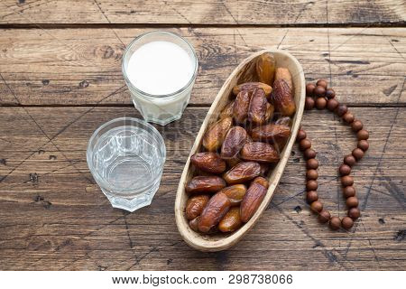 Dried Dates Fruits On A Branch, A Glasses Of Water And Milk On A Wooden Table. Traditional Fast Brea