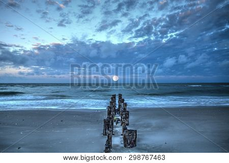Moonset At Dawn Over A Dilapidated Pier On The Beach In Port Royal