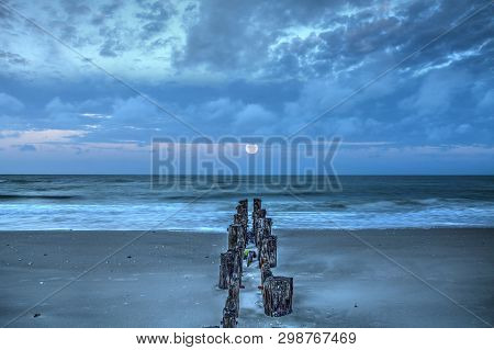 Moonset At Dawn Over A Dilapidated Pier On The Beach In Port Royal