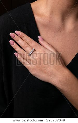 Womens Silver, Ring With Diamonds On Her Finger, On Black Background.