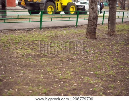 Selective Focus Shot Of A Bulldozer On The Street And Lawn In The Foregound