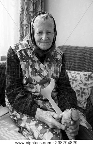 A Happy, Smiling Old Woman, Grandmother, Senior Sitting On The Couch, At A Cozy Home. Middle Europea