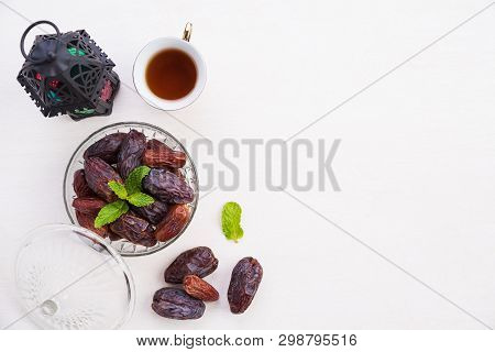 Ramadan Food And Drinks Concept. Ramadan Lantern With Tea, Dates Fruit And Mint Leaves On A White Wo
