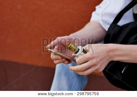 A Man Sits With A Phone And Vaping