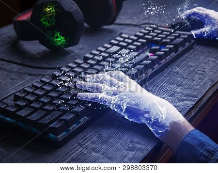 Childs Hands Covered With Ice On The Keyboard And Gaming Headphones On The Wooden Table. The Concept