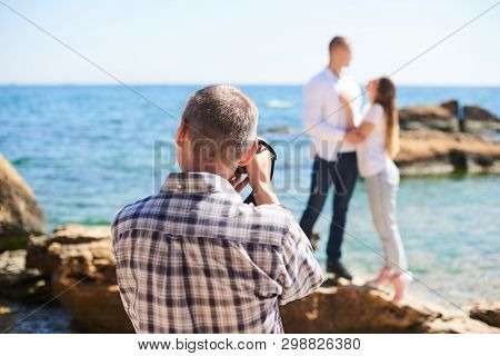 Photographer And Couple In Love, Beach Photo Shooting At Sunny Day, Man Taking Pictures Of Young Wom