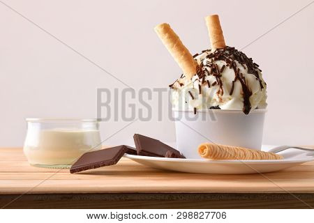 Cream And Choco Ice Cream Decorated With Chocolate Chips And Waffles On A Plate On A Wooden Table. H