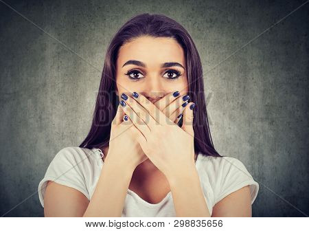 Scared Woman Covers Her Mouth To Keep It Quiet Isolated On Gray Background