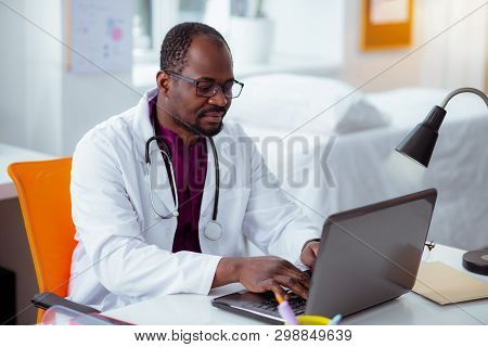 Bearded Dark-skinned Medical Scientist Working On Laptop