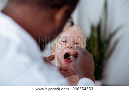 Close Up Of Blonde Girl Opening Mouth While Coming To Doctor