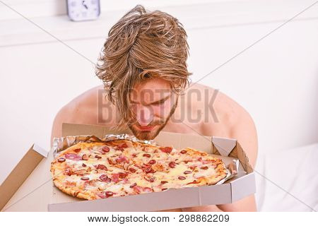 Food Delivery Service. Portrait Of Lazy Muscular Man Eating Pizza While Laying On A Bed At Home. Man