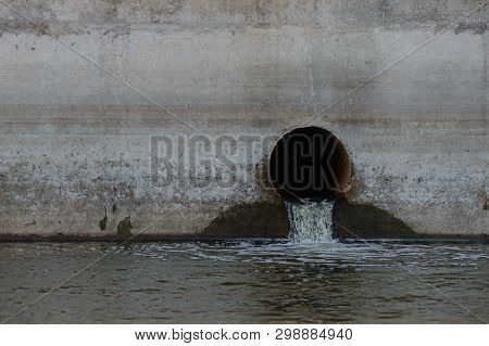 Sewer Pipe In A Concrete Wall From Which Water Flows Into The Reservoir