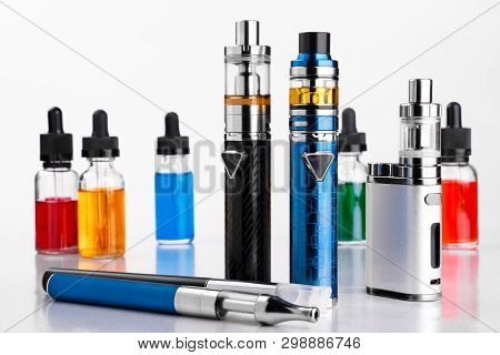 Electronic Cigarettes And Bottles With Vape Liquid On White Background