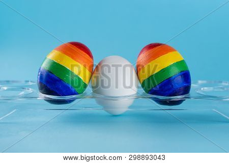 Lgbt Family. Eggs With Lgbt Flag Color And White Baby Egg On Blue Background. Creative Idea For Illu