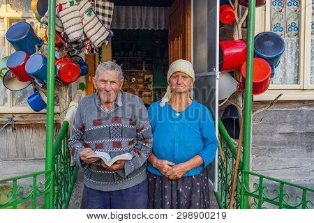 Barsana, Romania - August 2nd, 2018: A Couple Of Elderly Villagers, In Front Of Their Decorated Hous