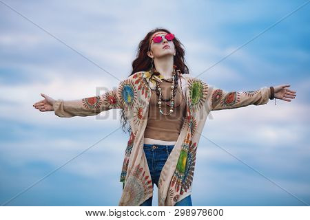 A portrait of a fashion female model against the sky in a coutryside. Contemporary bohemian style. Spirit of freedom. Fashion shot. Bohemian, bo-ho style.