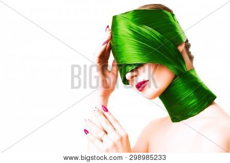 A close up portrait of a beautiful girl with a head rolled up in a leave posing in the studio over the white background. Beauty, nature, make up.