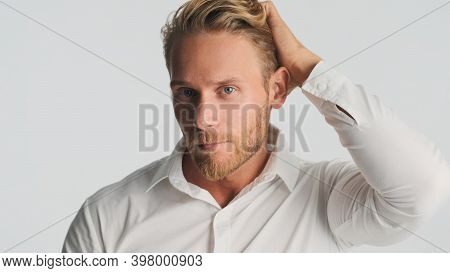 Handsome Bearded Businessman In Shirt Confidently Preening His Hair Looking In Camera Over White Bac