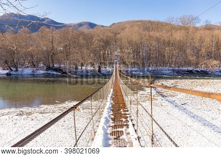 Suspention Bridge Over The Mountain River Winter View.
