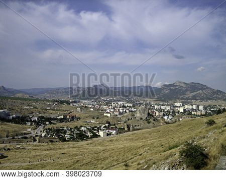 The City Of Sudak. The surroundings of the monument of architecture of the Genoese fortress. City buildings are closely adjacent to the historical fortress walls and towers.