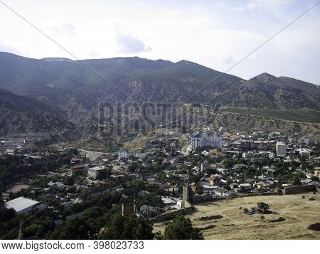 The City Of Sudak. The surroundings of the monument of architecture of the Genoese fortress. City buildings are closely adjacent to the historical fortress walls and towers.