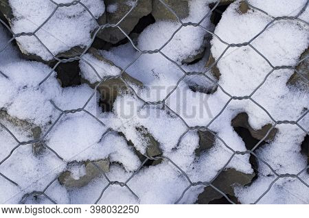 Background Large Mountain Sharp And Round Stones Enclosed Under A Steel Mesh In The Form Of A Honeyc